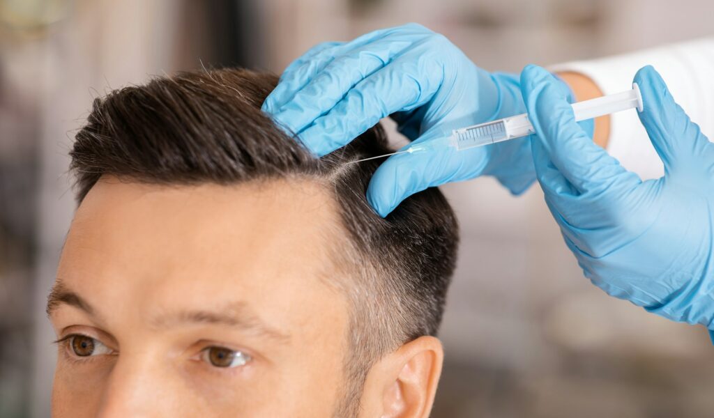 Handsome man having hair treatment at beauty salon